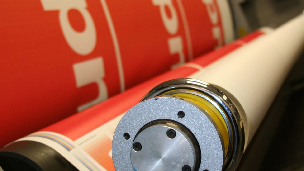 Close-up of printing rollers with red printed sheet